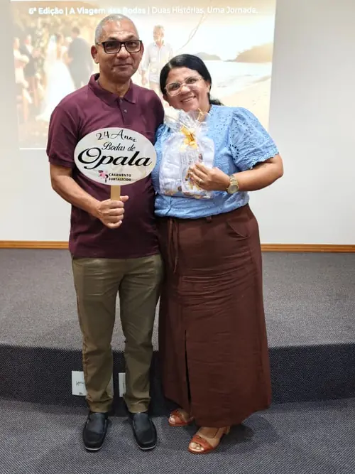 Casal da Viagem das Bodas segurando a plaquinha de 24 anos de casados, Bodas de Opala